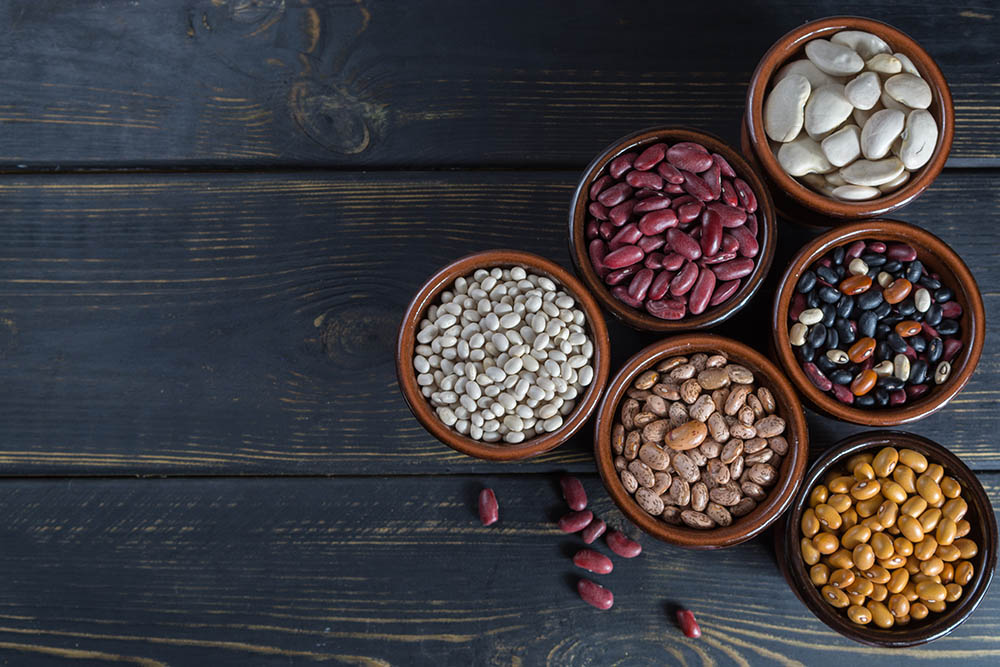 Assortment of beans on black wooden background. Soybean, red kidney bean, black bean,white bean, red bean and brown pinto beans