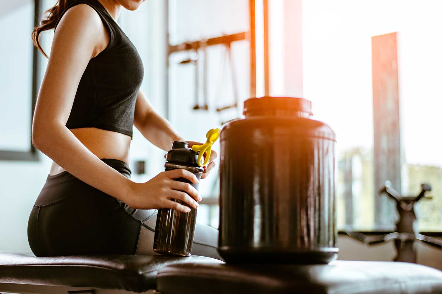 Relaxing after training.beautiful young woman looking away while sitting at gym.young female at gym taking a break from workout.woman brewing protein shake.