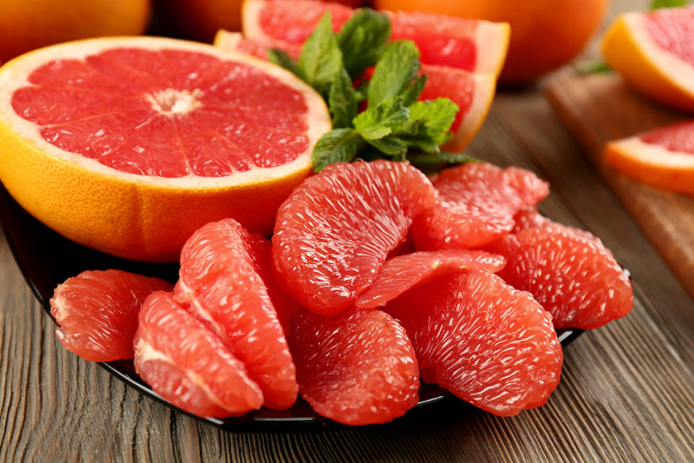Juicy grapefruit pieces with fresh mint in a bowl, close up
