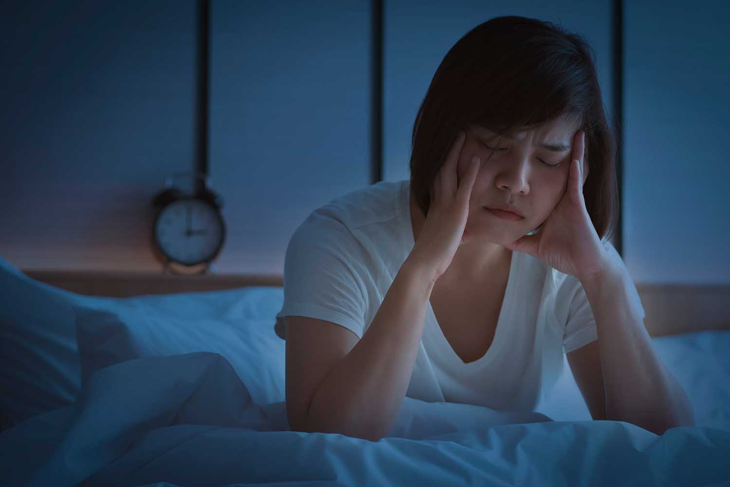 Insomnia in middle-aged women. An Asian woman tries to sleep but she cannot sleep because she has anxiety and stress from work. This symptom should be seen by a doctor for treatment.