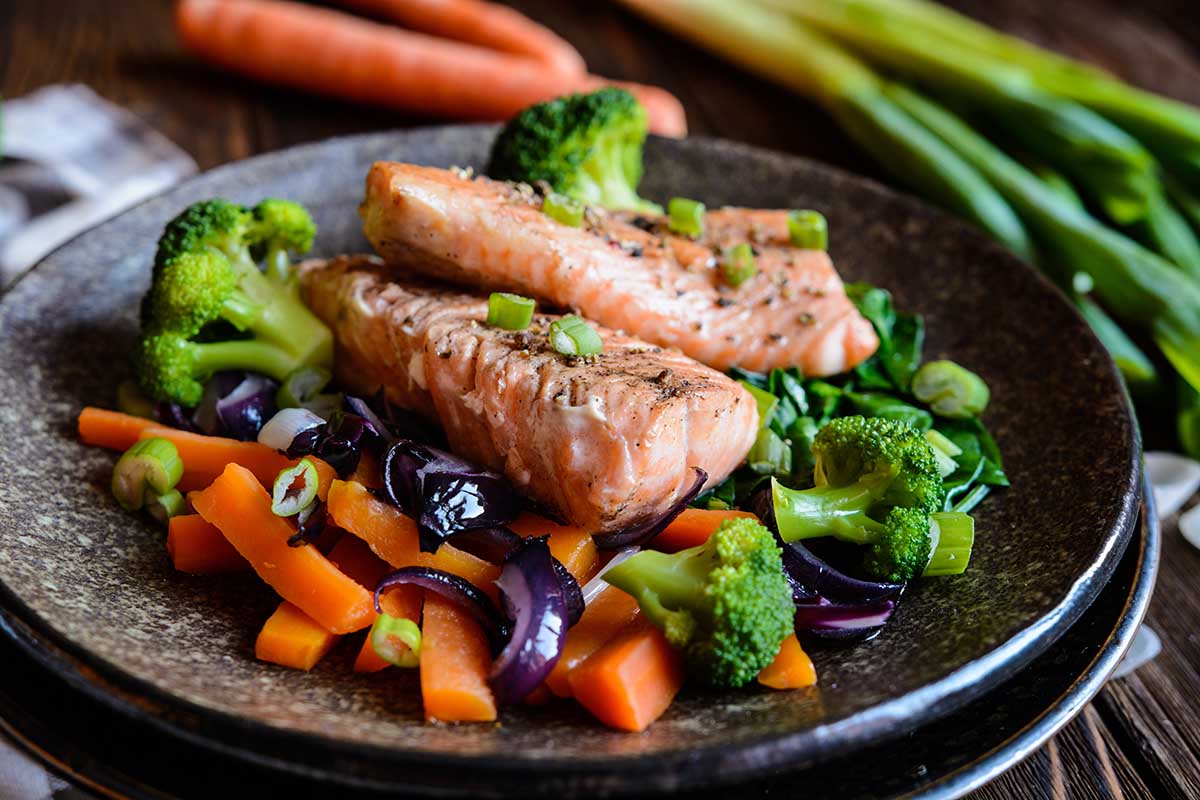 Fried steaks with steamed carrot, broccoli, onion and spinach