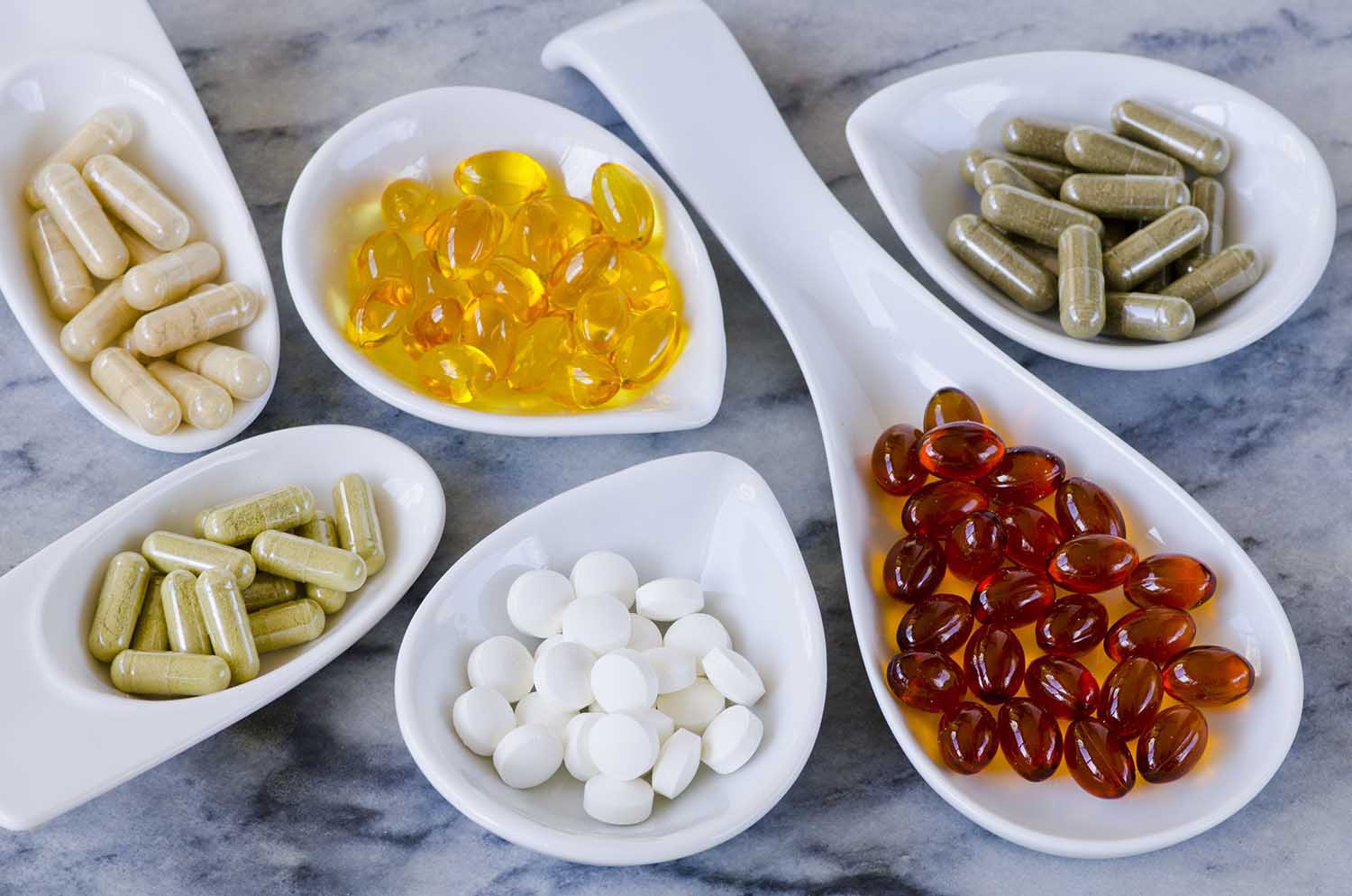 Variety of dietary supplements, including capsules of Garlic, Evening Primrose Oil; Artichoke Leaf; Olive Leaf; Magnesium and Omega 3 Fish Oil.Selective focus. Taken in daylight.