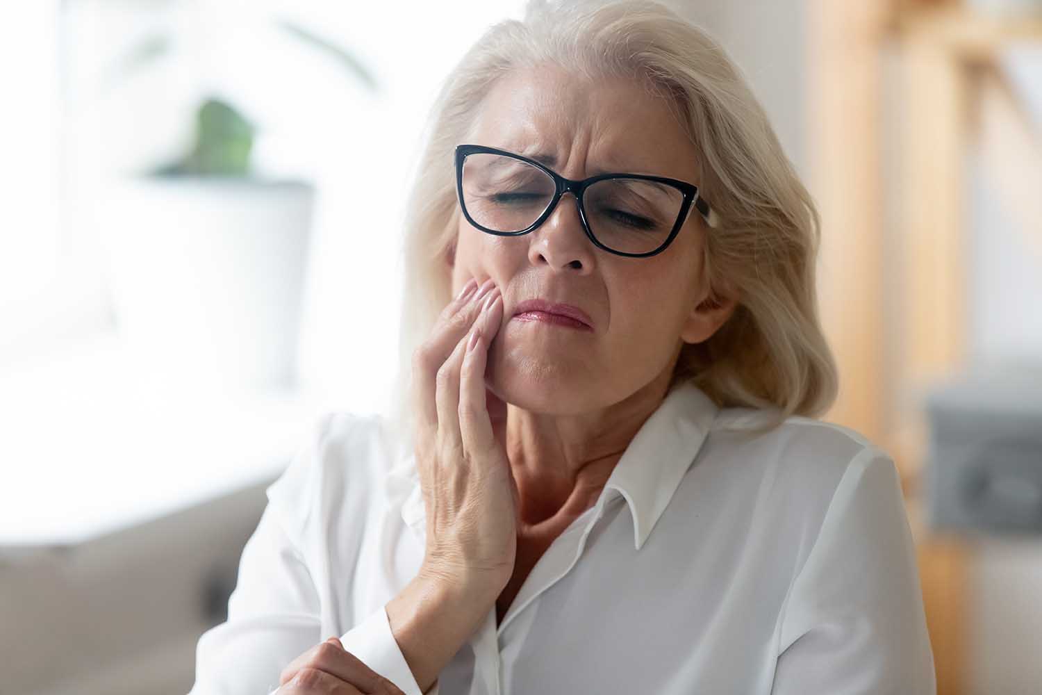 Hurt senior female worker in glasses feel stressed suffering from severe toothache at workplace, unhappy aged woman employee in glasses feel bad stressed having teeth pain, need dental treatment