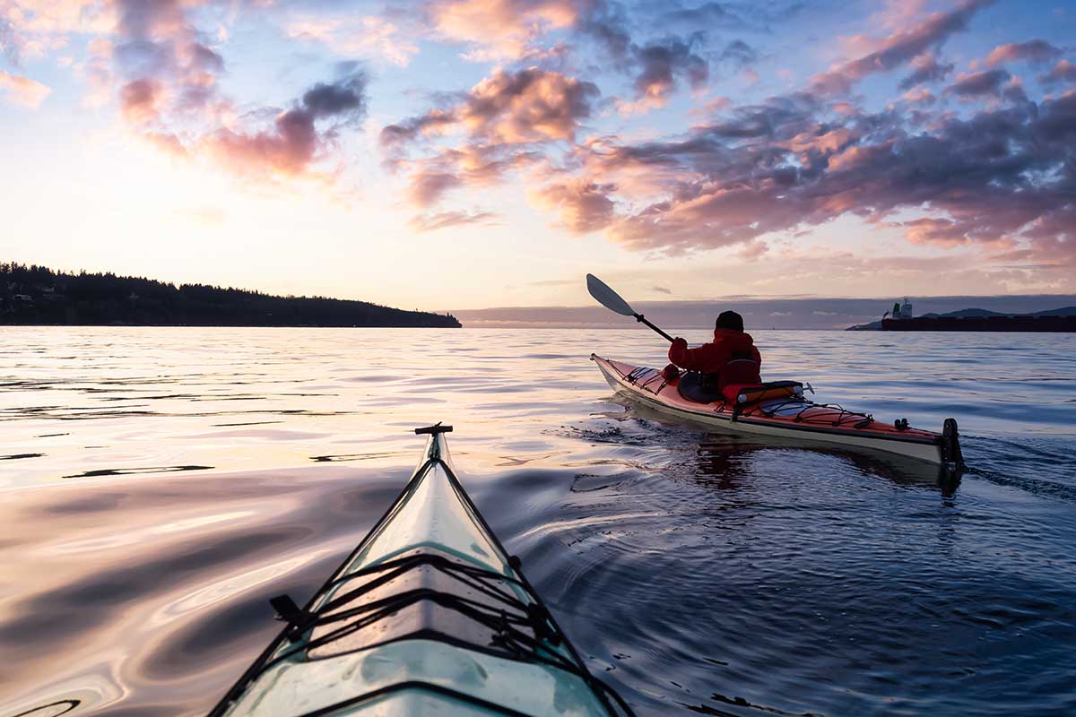 Adventurous Man Sea Kayaking in the Pacific Ocean. Dramatic Colorful Sky Art Render. Taken in Jericho, Vancouver, British Columbia, Canada.