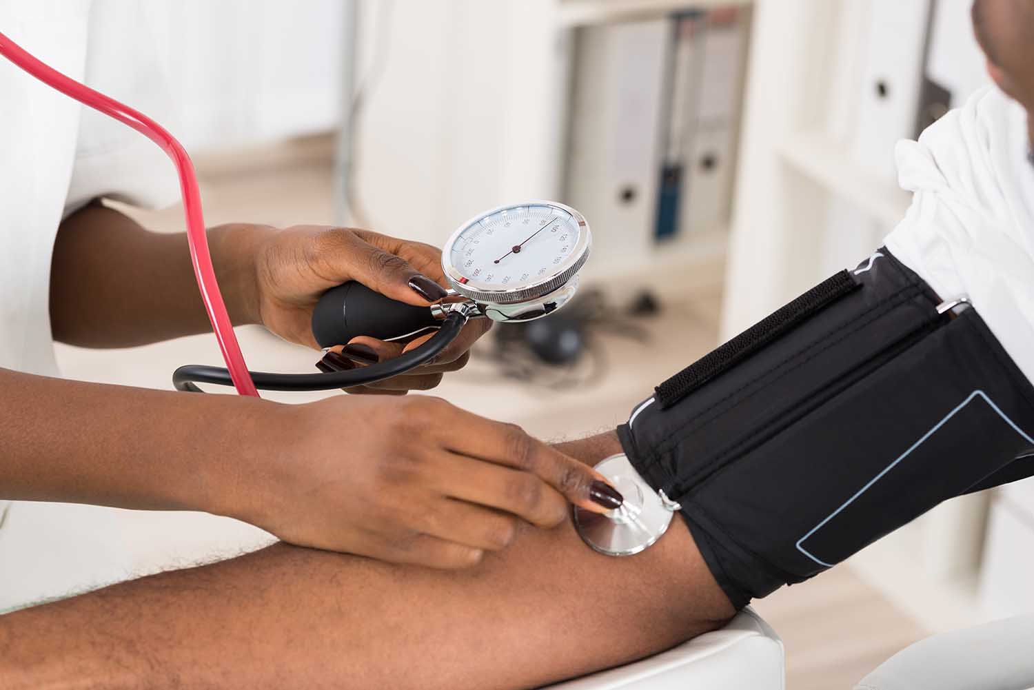 Close-up Of Doctor Measuring Patients Blood Pressure With Stethoscope
