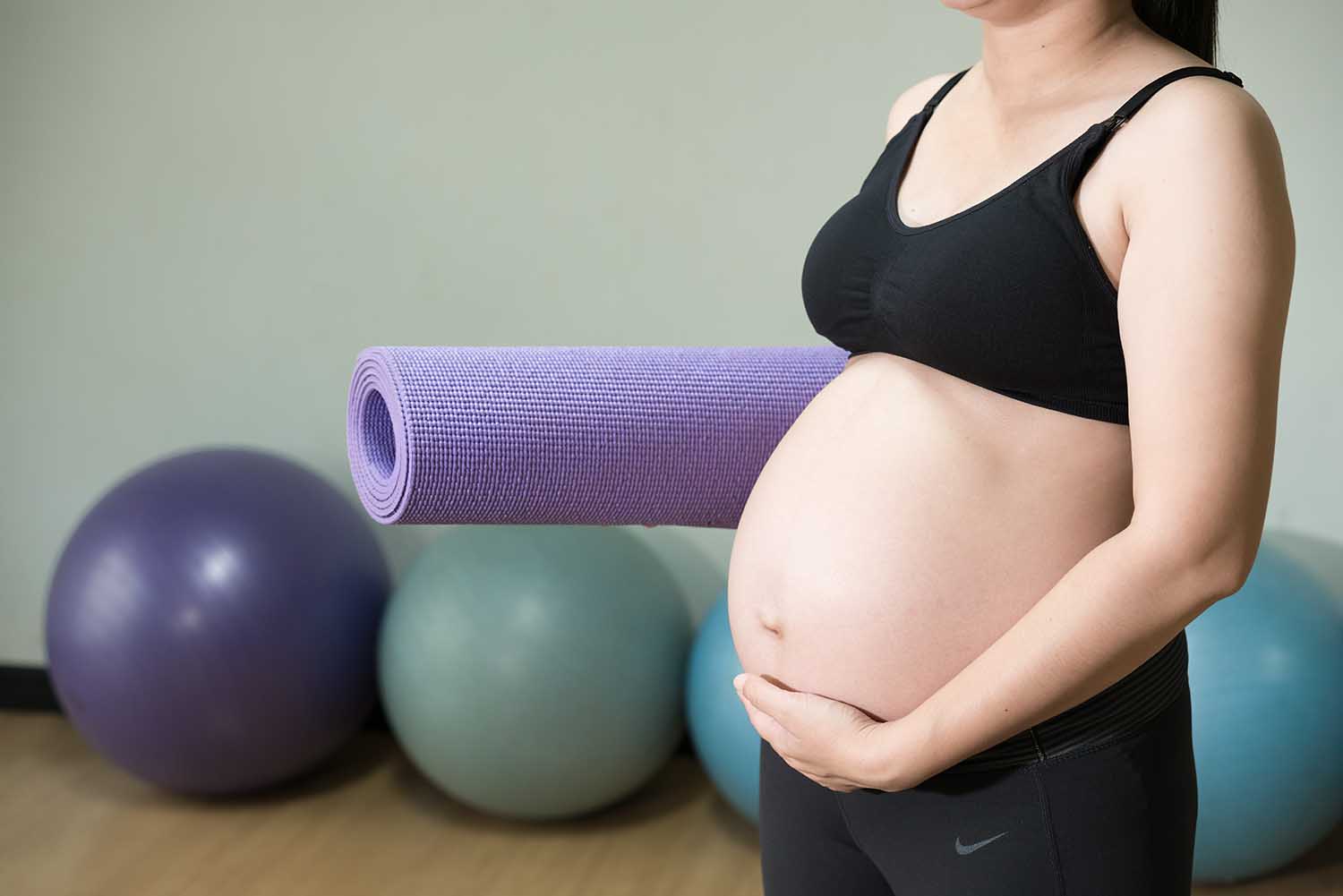 pregnancy, sport, fitness, people and healthy lifestyle concept - happy pregnant woman with mat in gym
