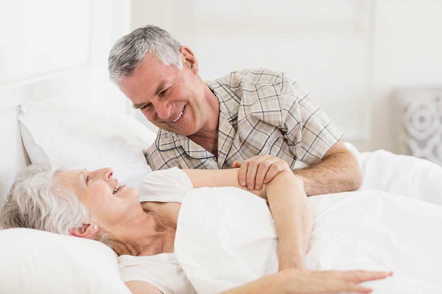 Happy senior couple at bed at home