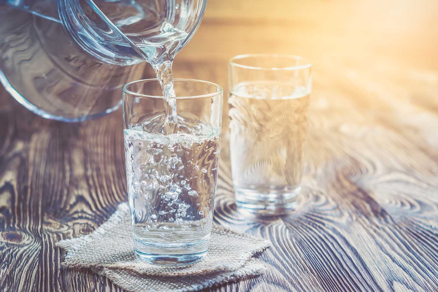 Glass of water on a wooden table. Water was poured into the beaker. Selective focus. Shallow DOF. With lighting effects. With copy space