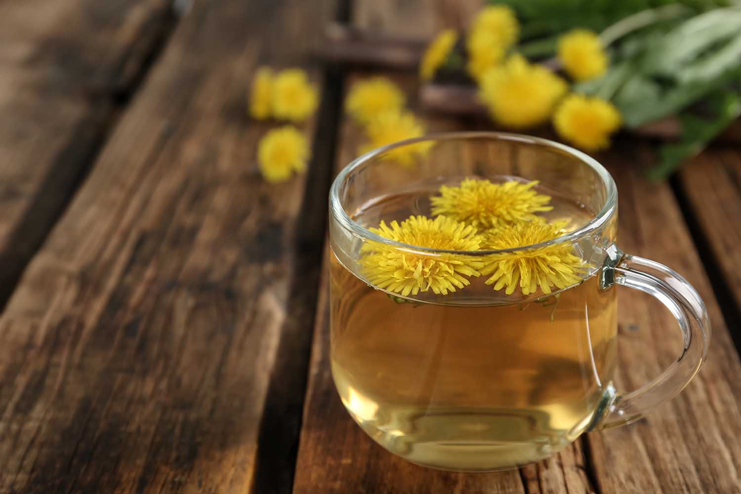 Delicious fresh dandelion tea on wooden table, closeup. Space for text