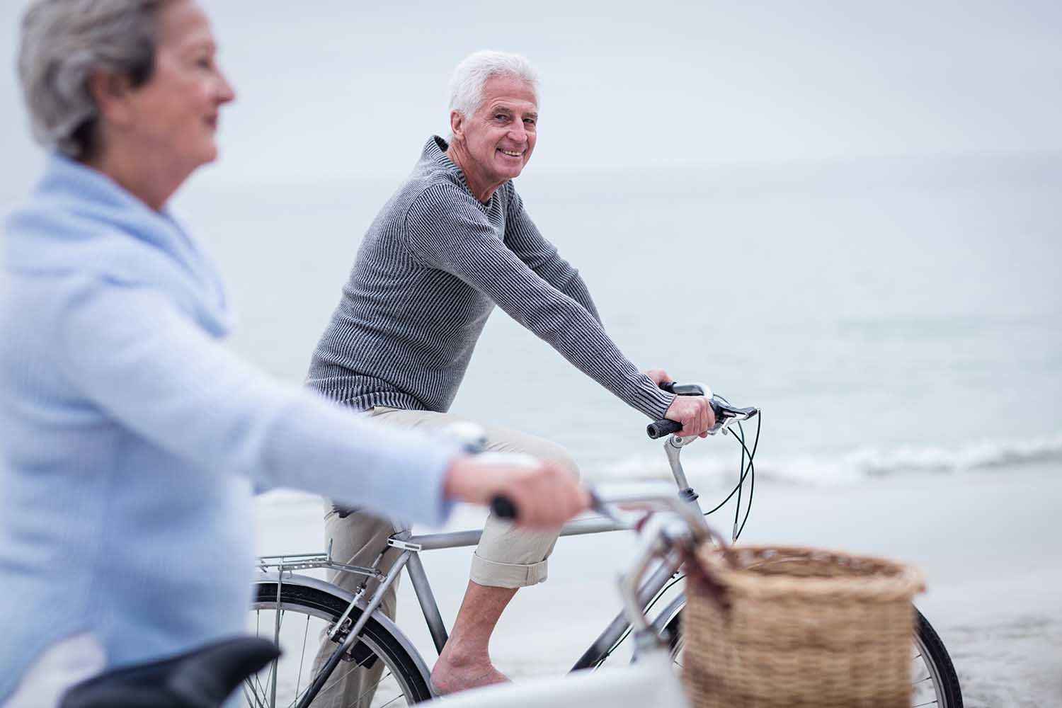 Senior couple having ride with their bike on the beach