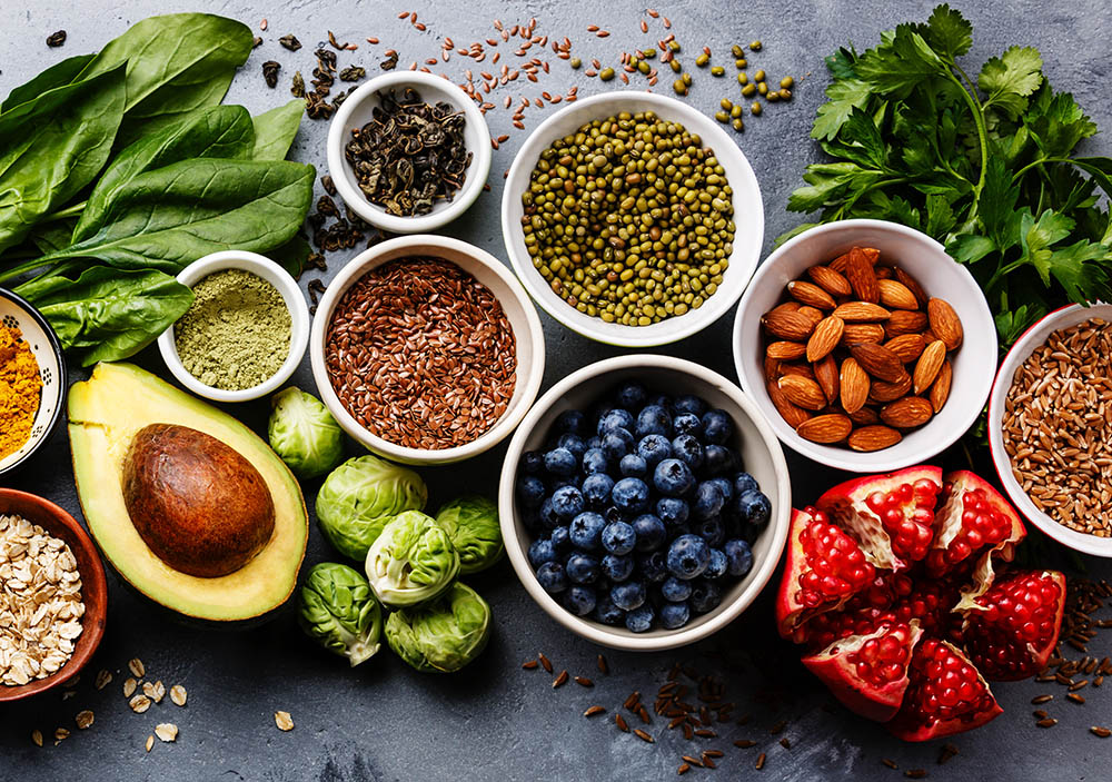 Healthy food clean eating selection: fruit, vegetable, seeds, superfood, cereal, leaf vegetable on gray concrete background