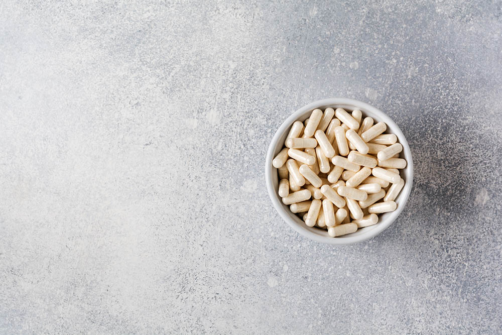 Collagen pills on gray concrete background. Healthy lifestyle concept. Copy space