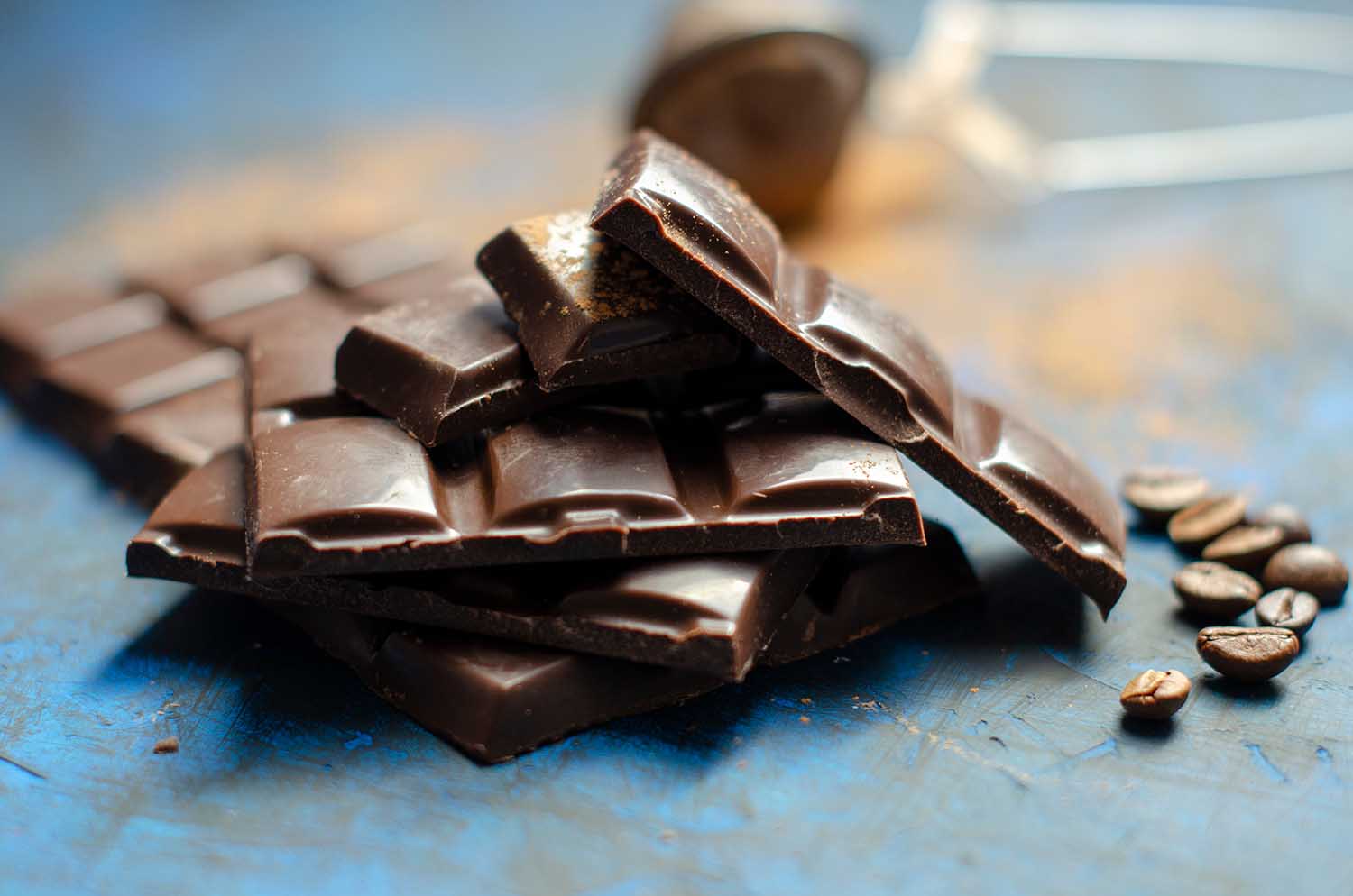 slices of dark chocolate with cocoa on a dark blue background