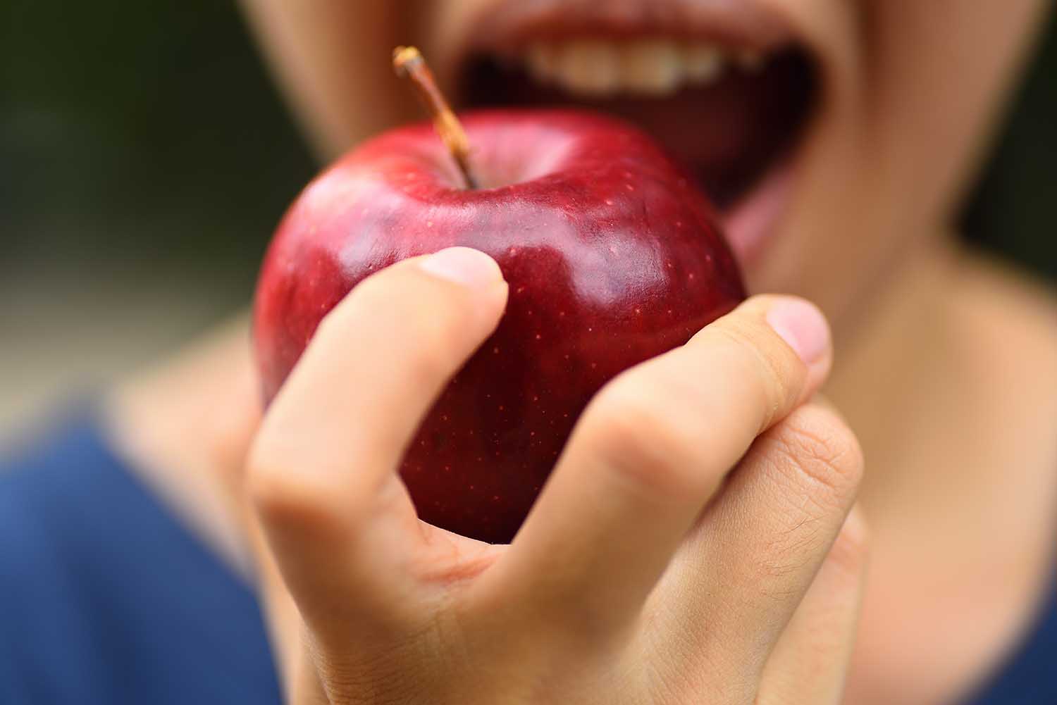 The woman holding fresh apple to eating