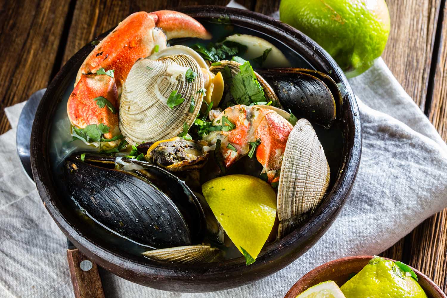 Seafood shellfish soup of mussels, crabs, clams and other shellfish served in clay bowls. typical chilean dish Paila marina or Mariscal. Top view.