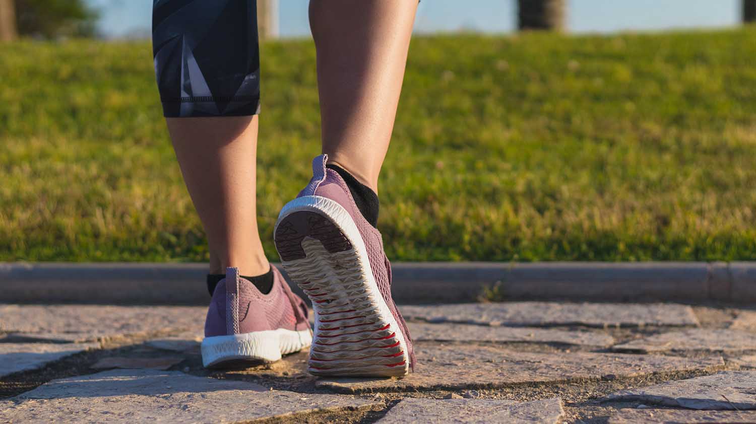 Athlete runner feet running in nature, closeup on shoe. Woman fitness jogging, active lifestyle concept