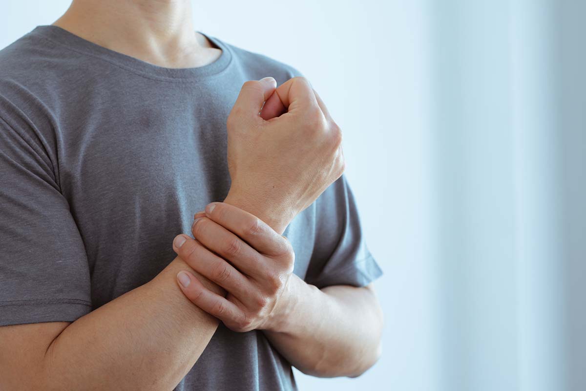 male arms holding his painful wrist caused by prolonged work on the computer, laptop,neurological disease concept. Numbness of the hand
