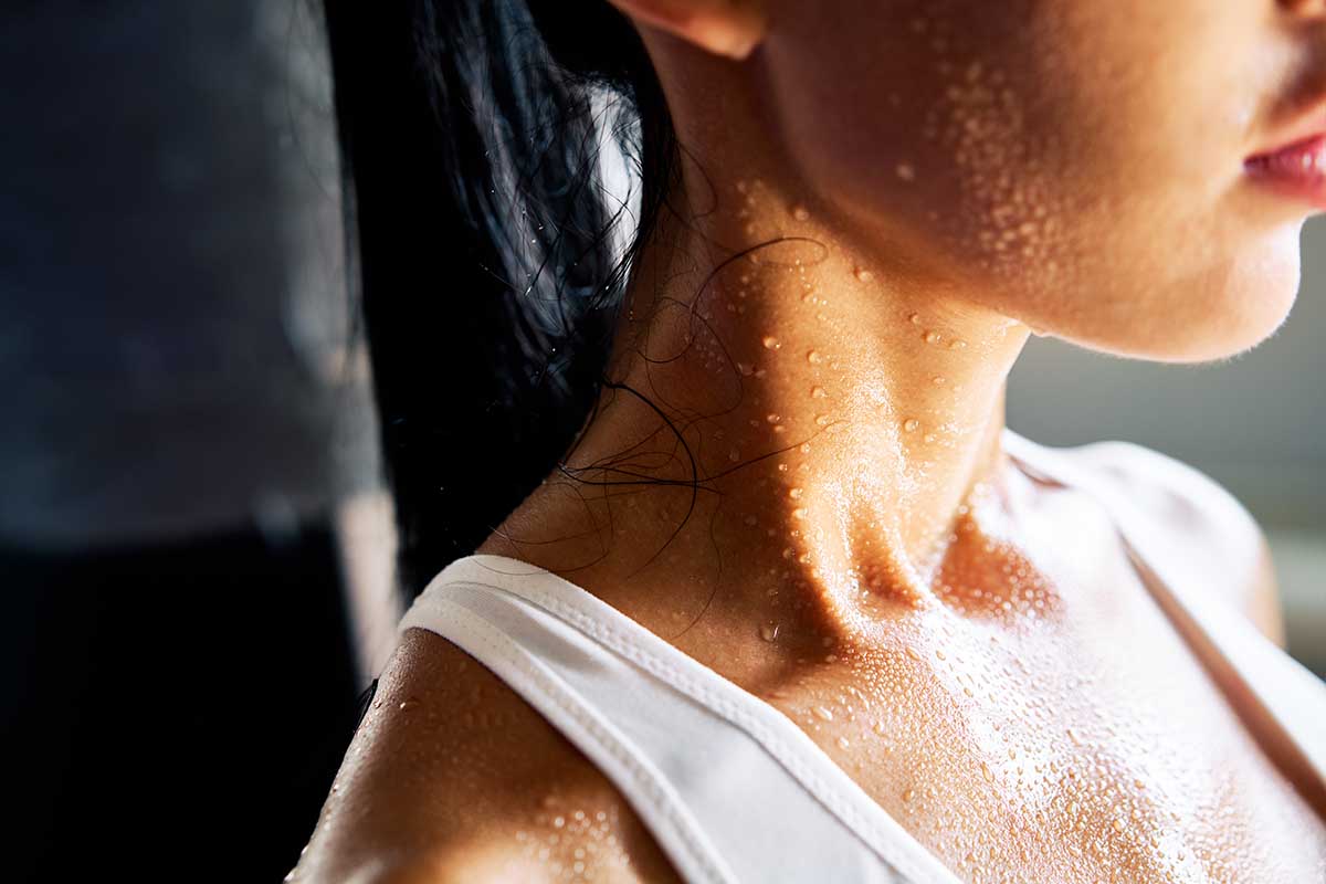 Close up shoulders and neck of a beautiful sporty girl in drop of sweat on skin after workout