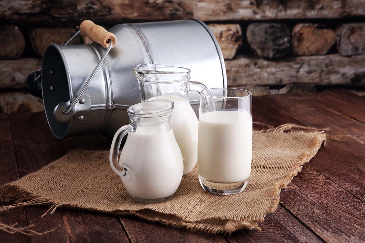 A jug of milk and glass of milk on a wooden table