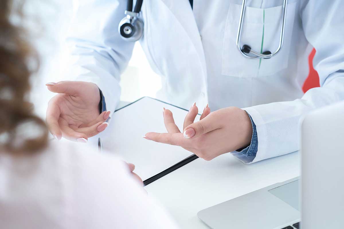 Patient listening intently to a female doctor explaining patient symptoms or asking a question as they discuss together in a consultation.