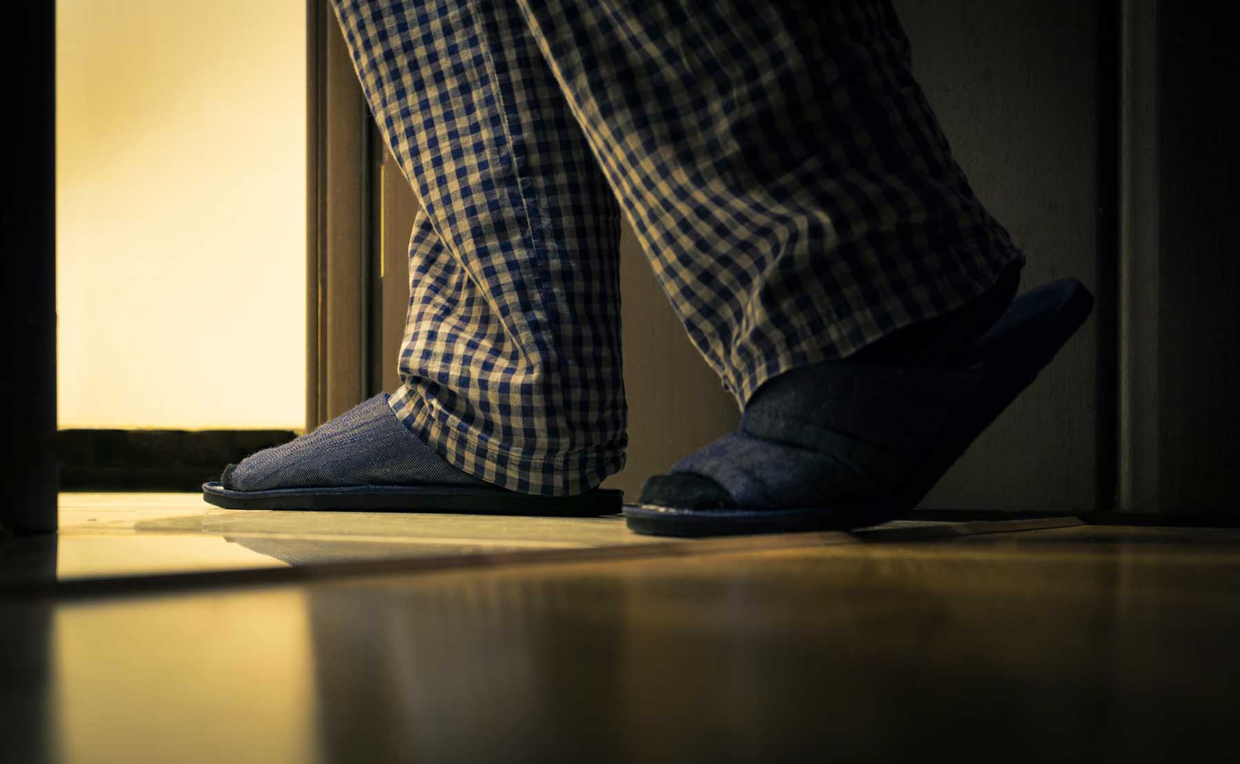 Adult man in pajamas walks to a bathroom at the night. Men's healths concept