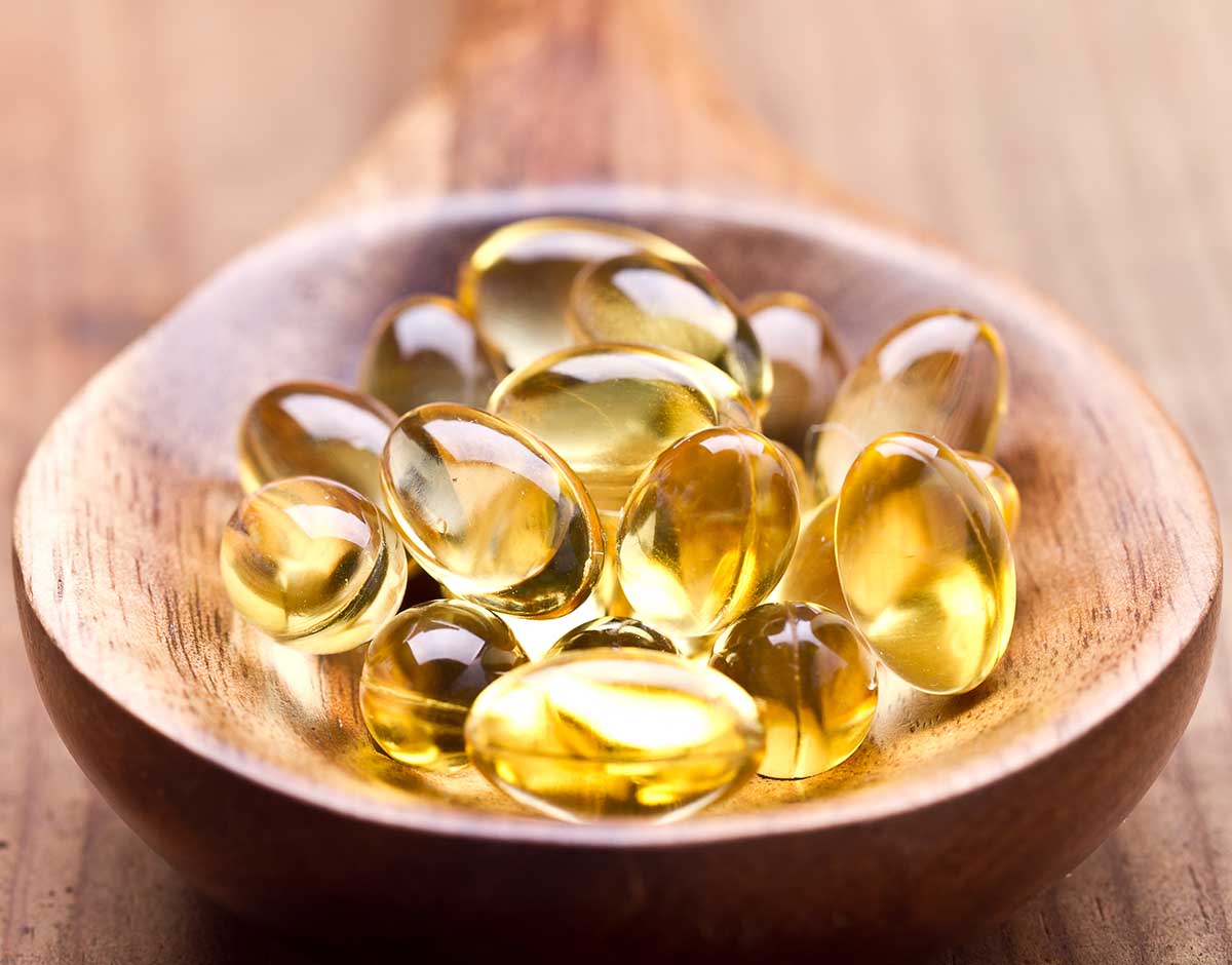 Cod liver oil omega 3 gel capsules isolated on wooden background