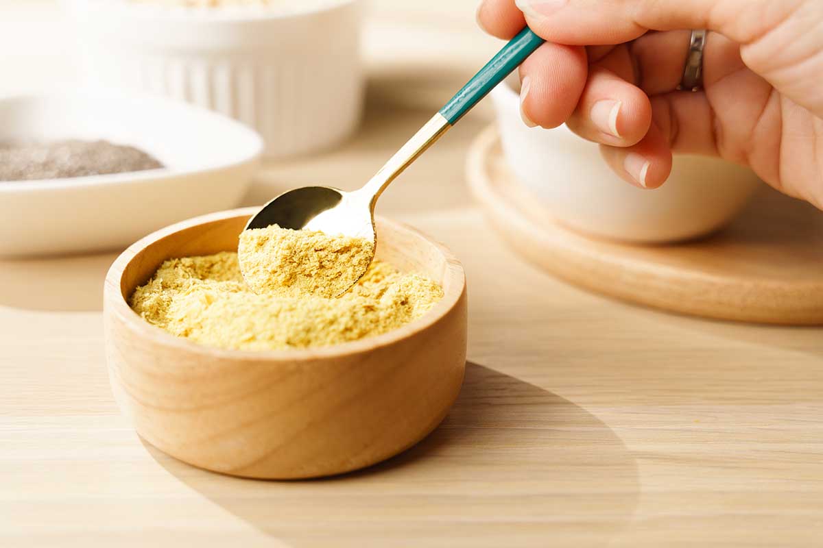 Nutritional yeast flakes in wooden bowl a great source of vitamins and minerals for vegan and plant-base diet contains amino acids, complete protein, Dairy free, Gluten free, Substitute, Superfoods.