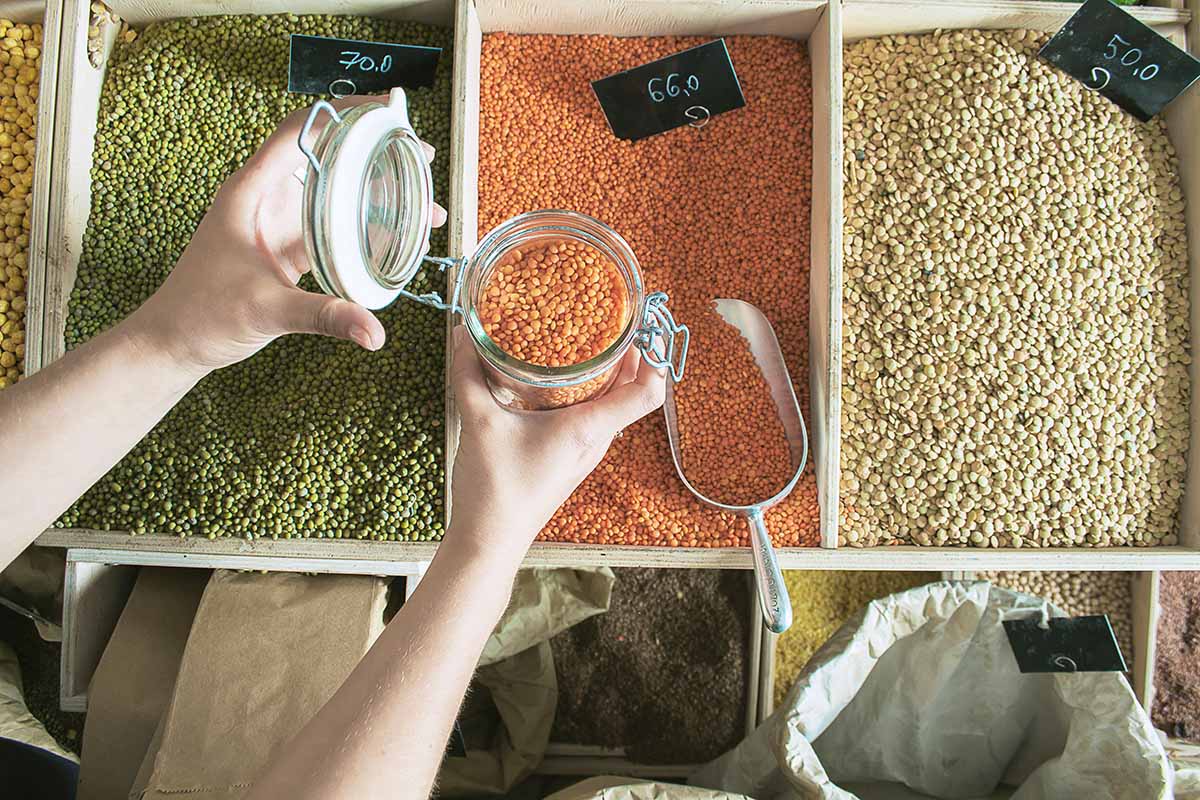 woman is buying products in zero waste shop with glass jars, cotton bags with out plastic packages