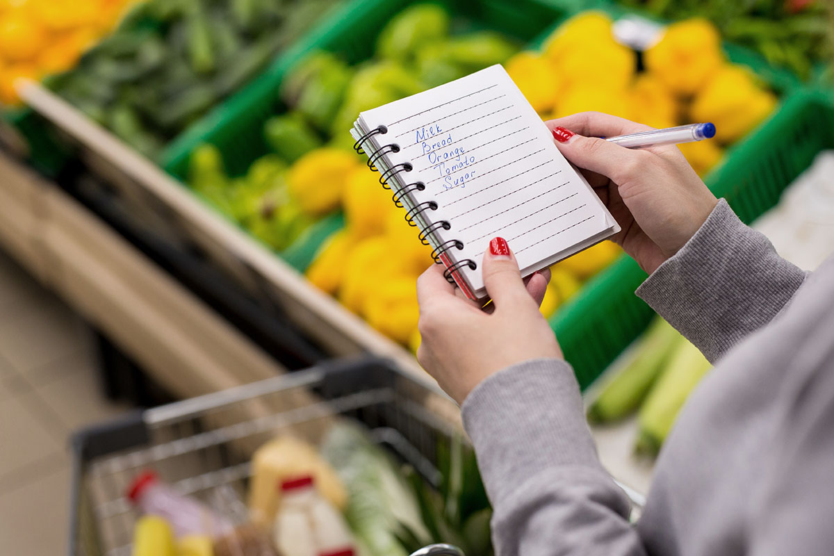Woman with notebook in grocery store, closeup. Shopping list on paper.