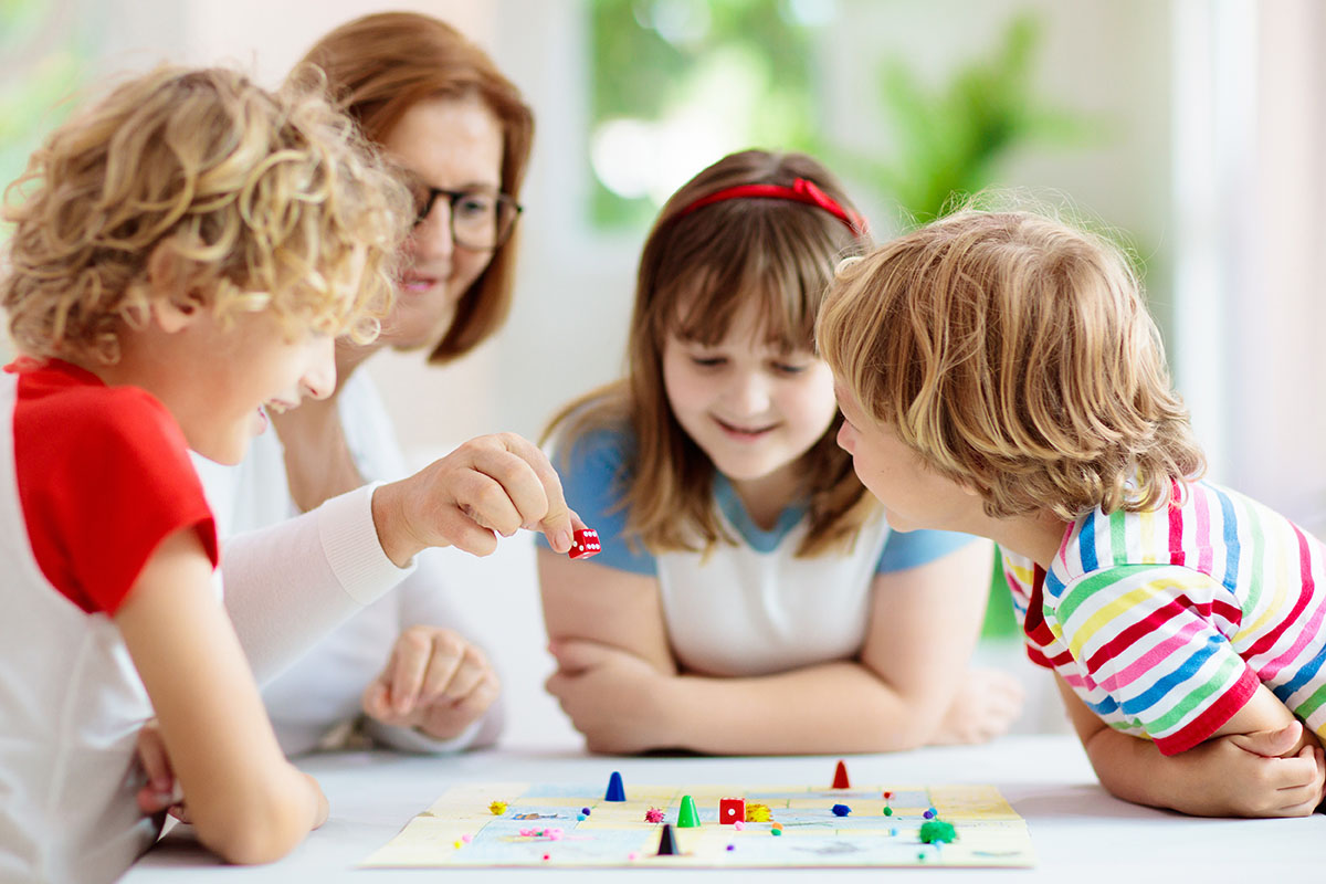 Family playing board game at home. Kids play strategic game. Little boy throwing dice. Fun indoor activity for summer vacation. Siblings bond. Educational toys. Friends enjoy game night.