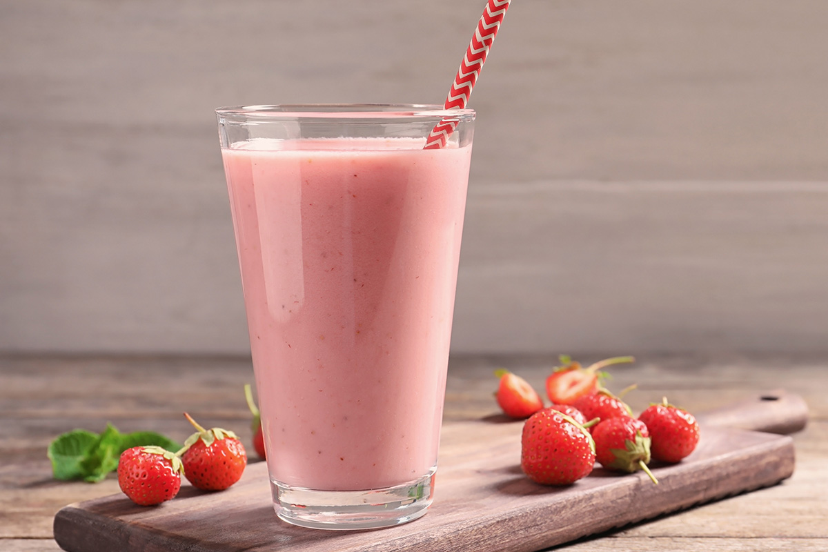 Glass with tasty strawberry smoothie on wooden table