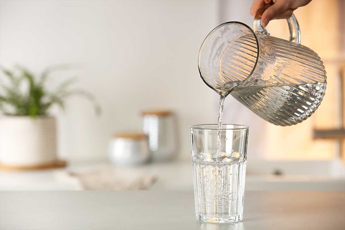 Woman filling a glass with water from a pitcher