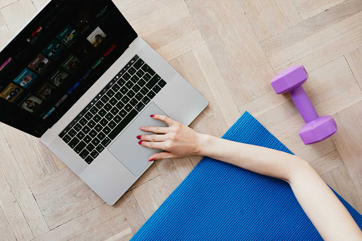 Woman scrolling on a laptop while working out