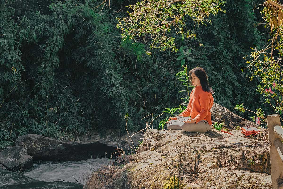 Man meditating on a rock overlooking a river